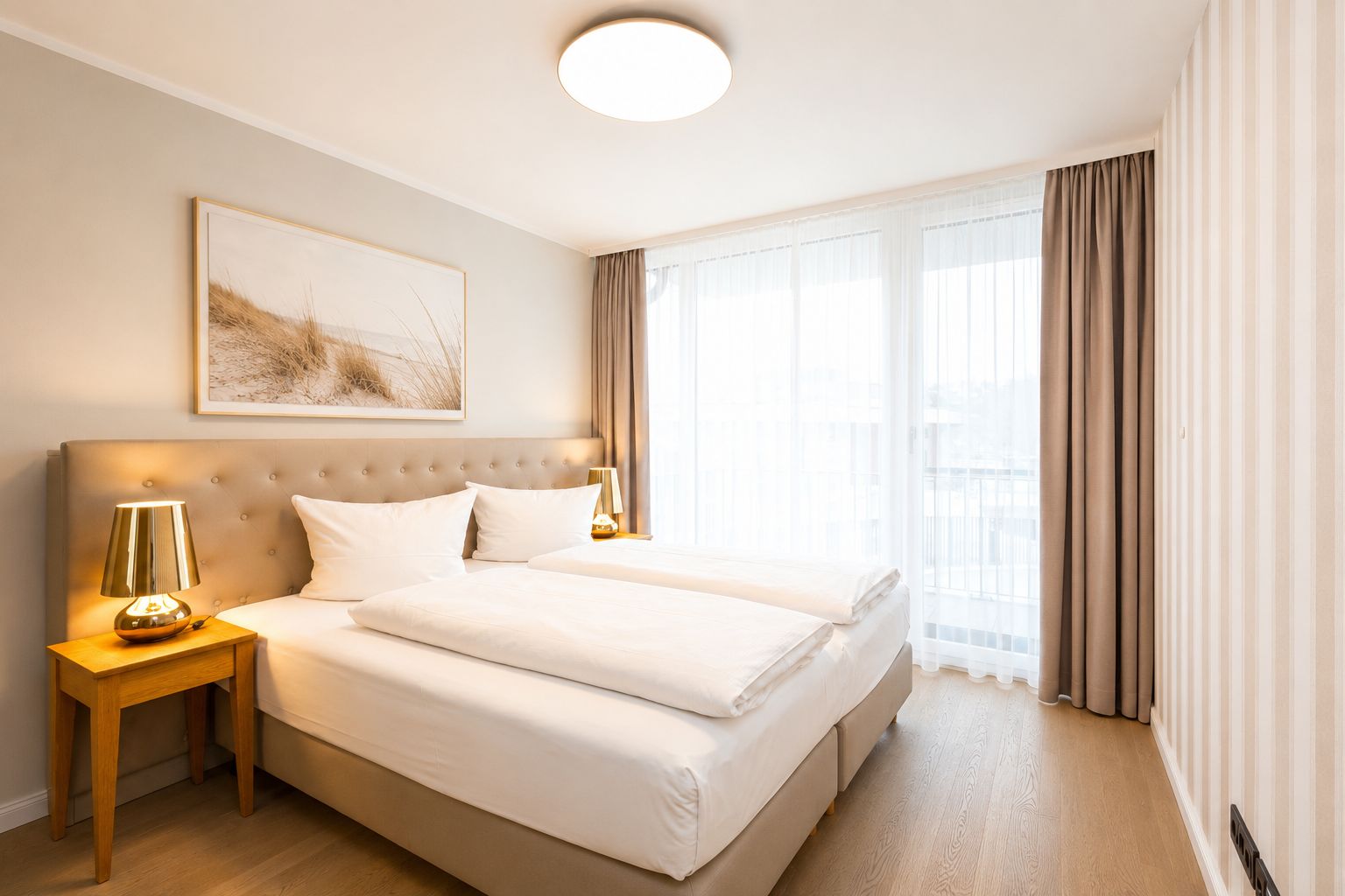 Modernes Schlafzimmer mit Doppelbett, zwei Nachttischen und großen Fenstern mit Vorhängen.