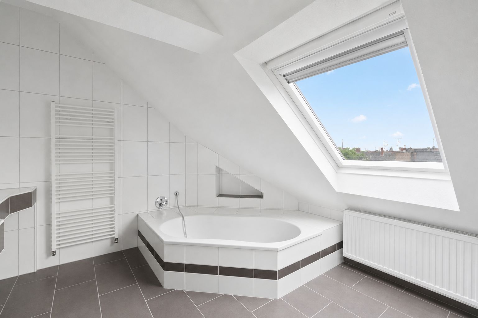 Modernes Badezimmer mit Badewanne unter einer Dachschräge und großem Fenster.