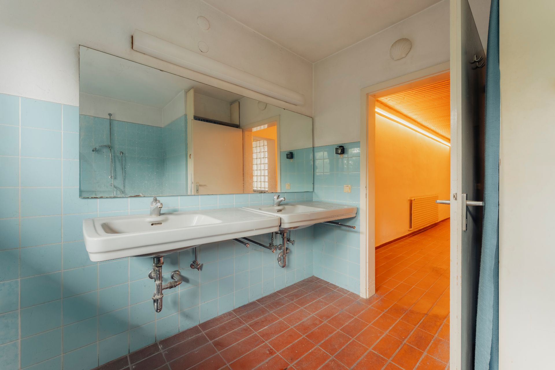 Badezimmer mit zwei weißen Waschbecken, Spiegel und blauen Wandfliesen.
