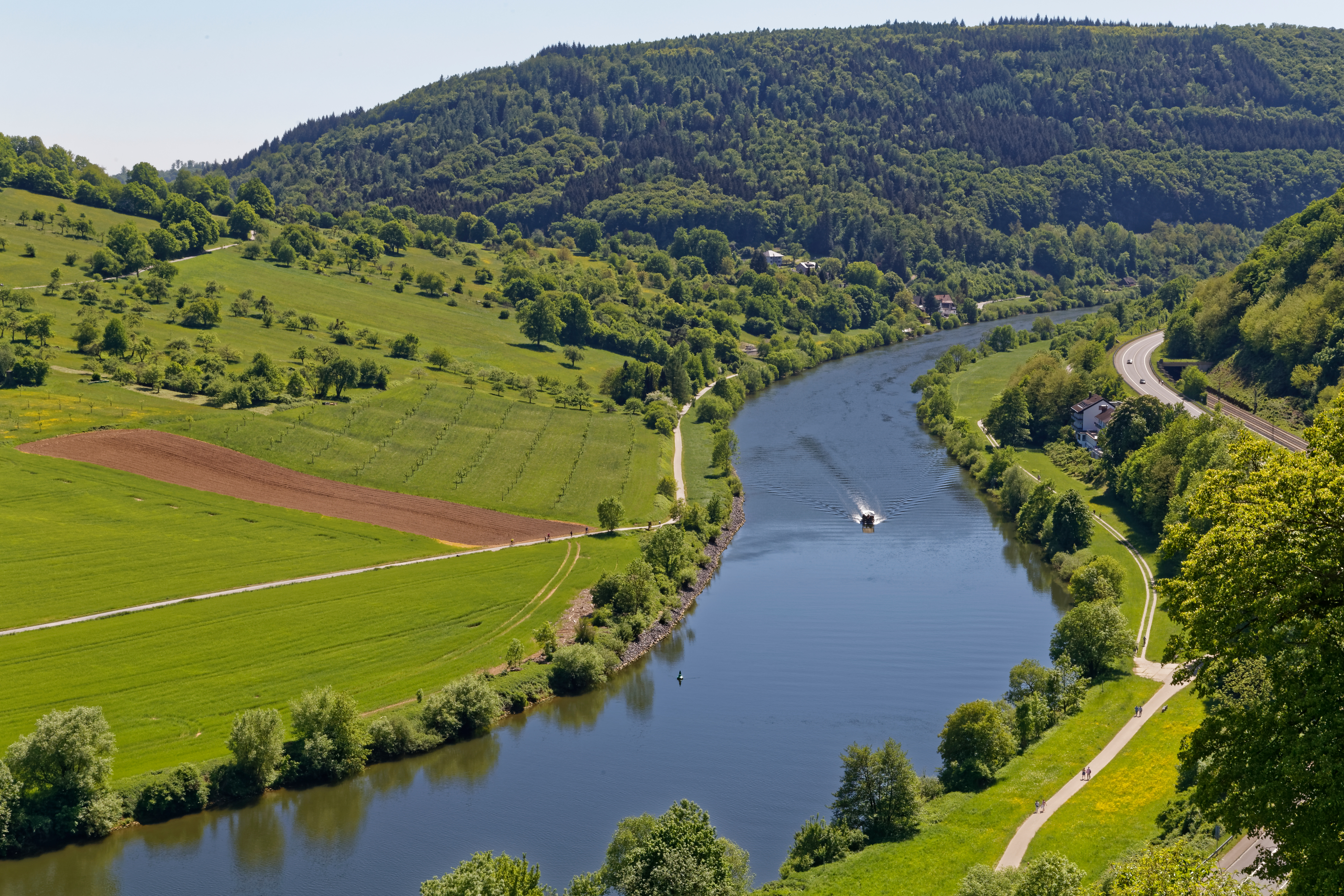 Fluss, der durch eine grüne Landschaft mit Feldern und Bäumen fließt, Boot auf dem Wasser.