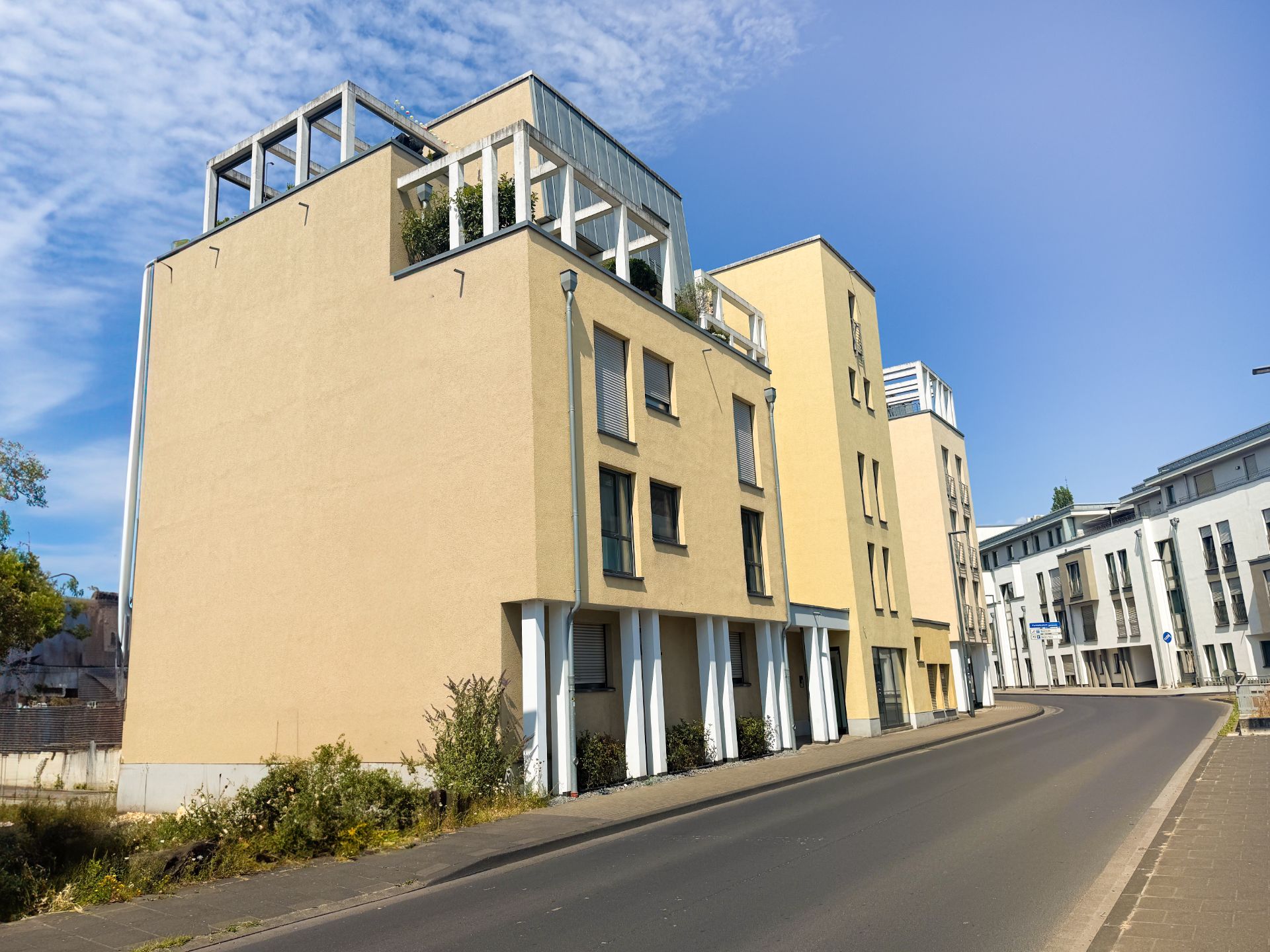 Modernes, mehrstöckiges Wohngebäude an einer Straße bei Tageslicht.