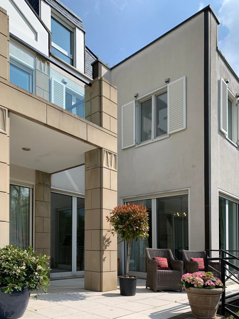 Moderner Hausinnenhof mit Sitzbereich, Pflanzen in Töpfen und großen Fenstern.