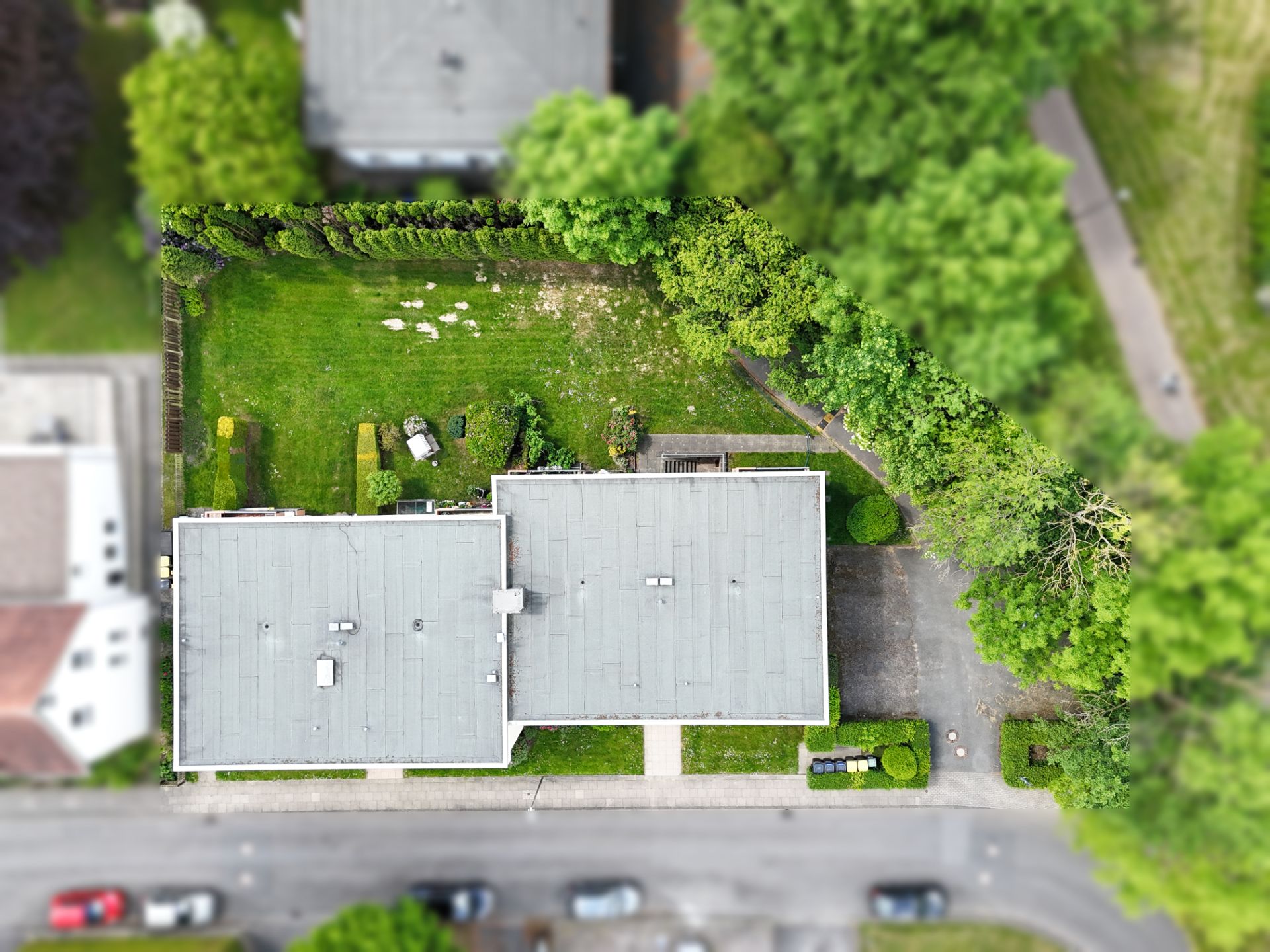 Luftaufnahme eines Wohngebäudes mit großem Garten und umliegenden Bäumen.