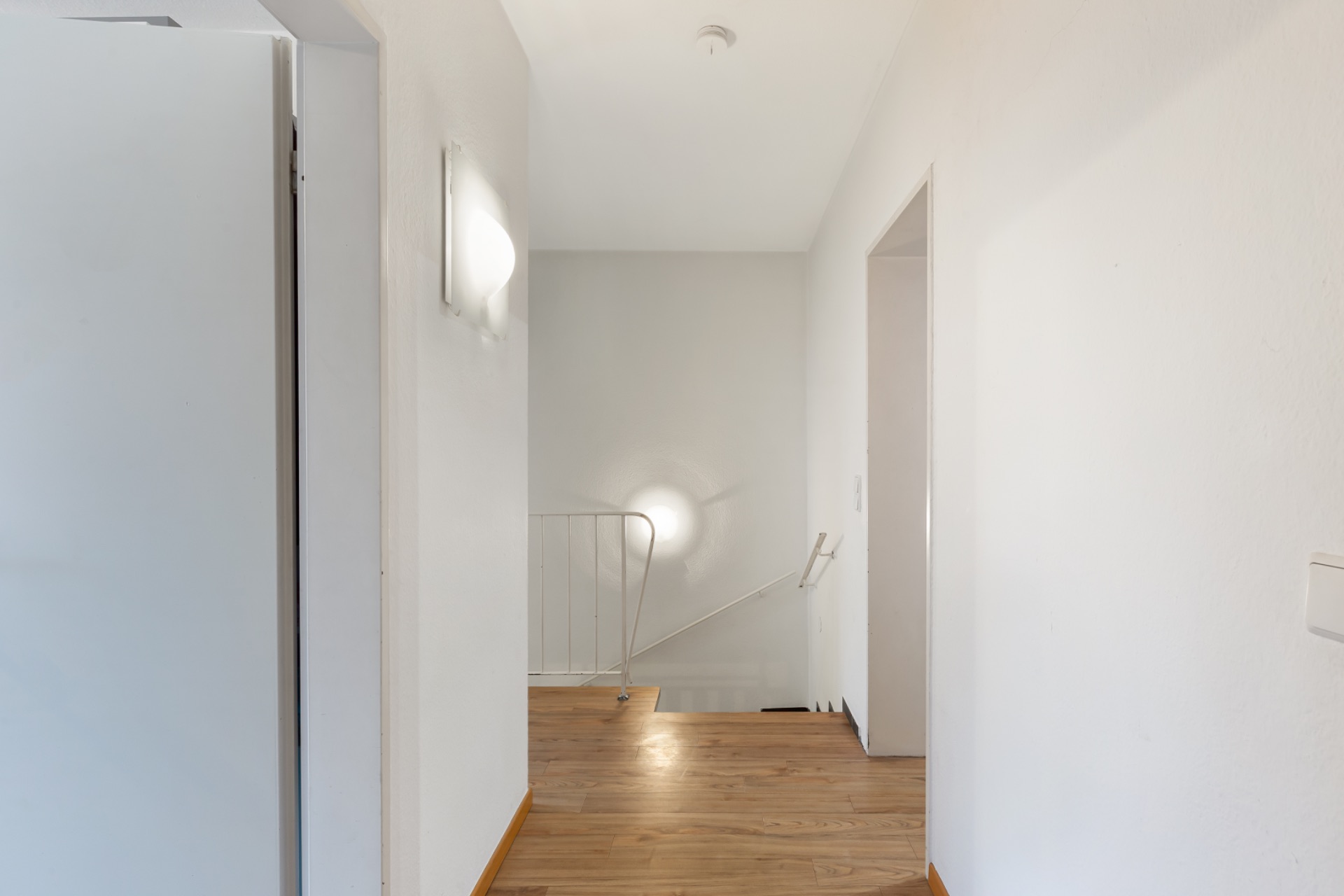 Heller Flur mit Holzfußboden und Treppe, Türen zu angrenzenden Räumen.