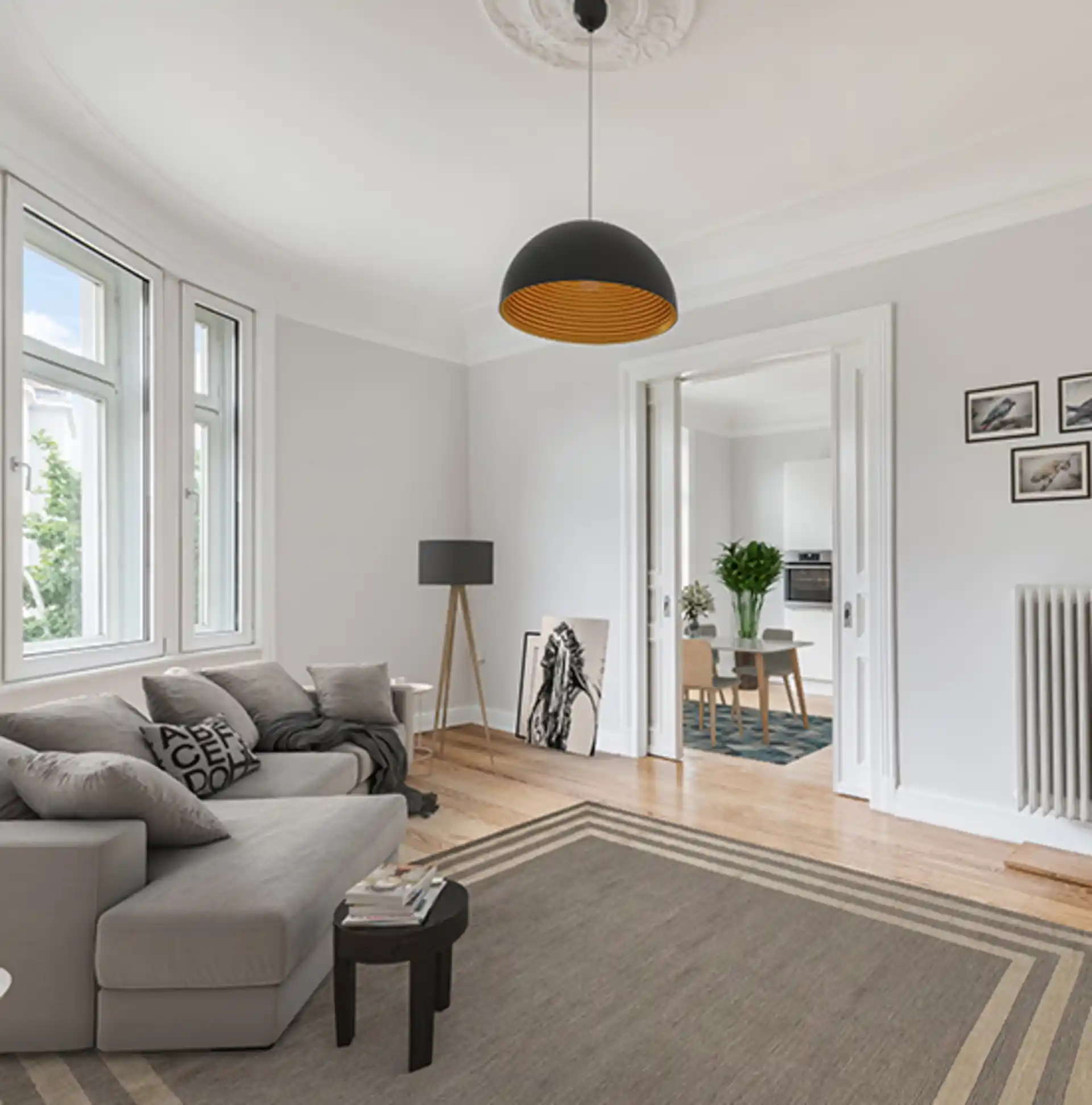 Helles Wohnzimmer mit grauem Sofa, Teppich und Blick ins Esszimmer mit Tisch und Stühlen.