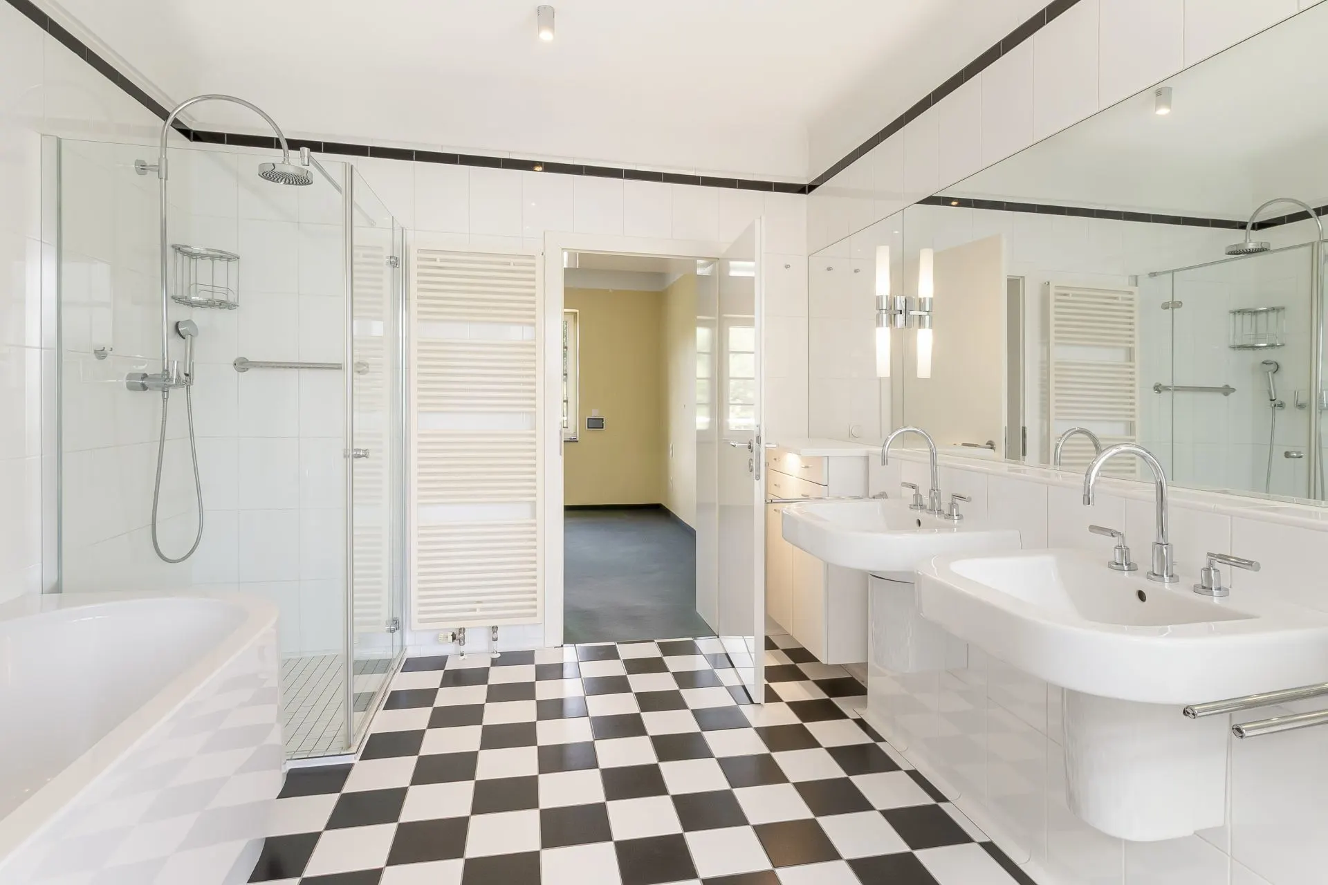 Helles Badezimmer mit Dusche, Badewanne, zwei Waschbecken und schwarz-weiß kariertem Boden.