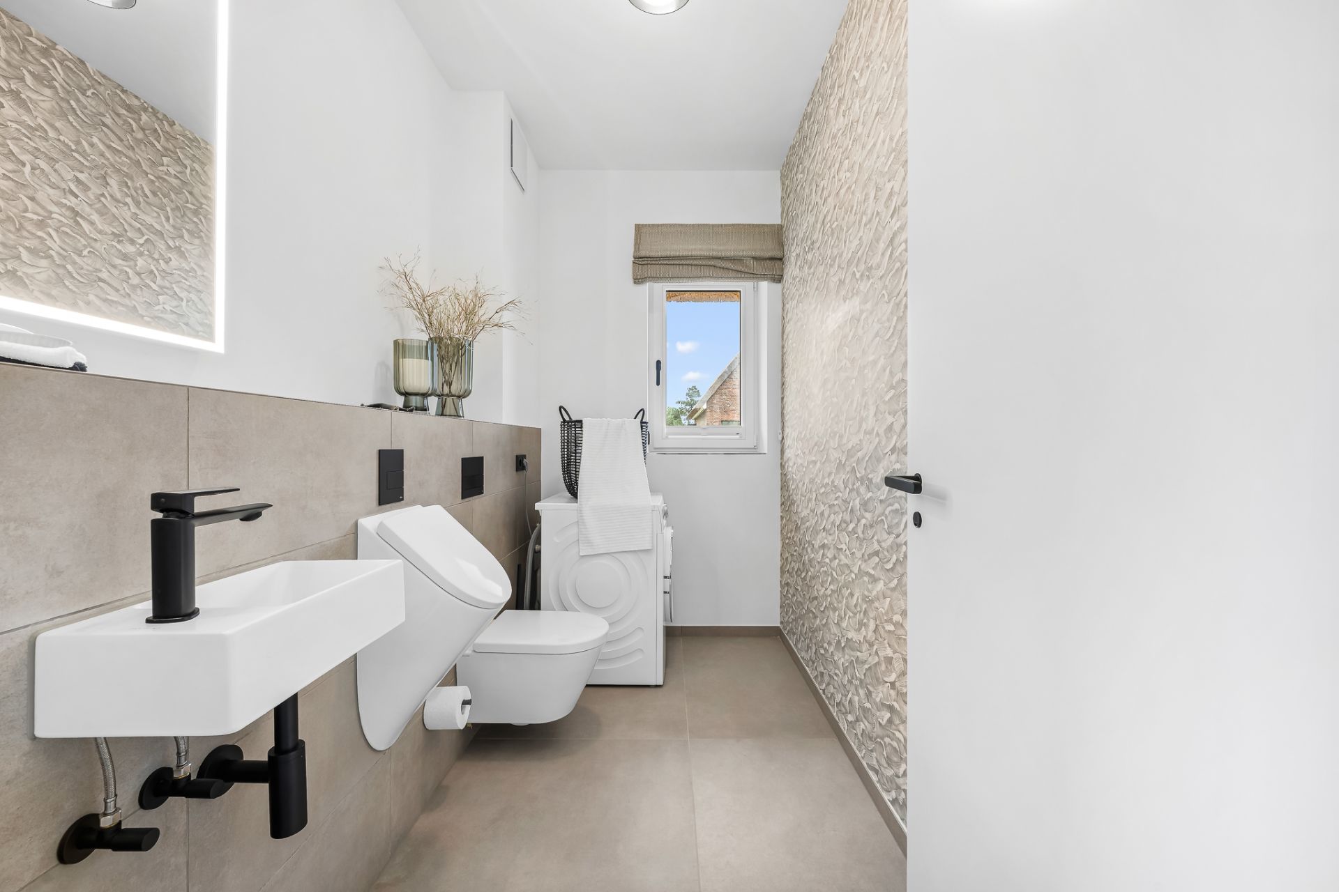 Modernes Badezimmer mit Waschbecken, Toilette, Waschmaschine und kleinem Fenster.