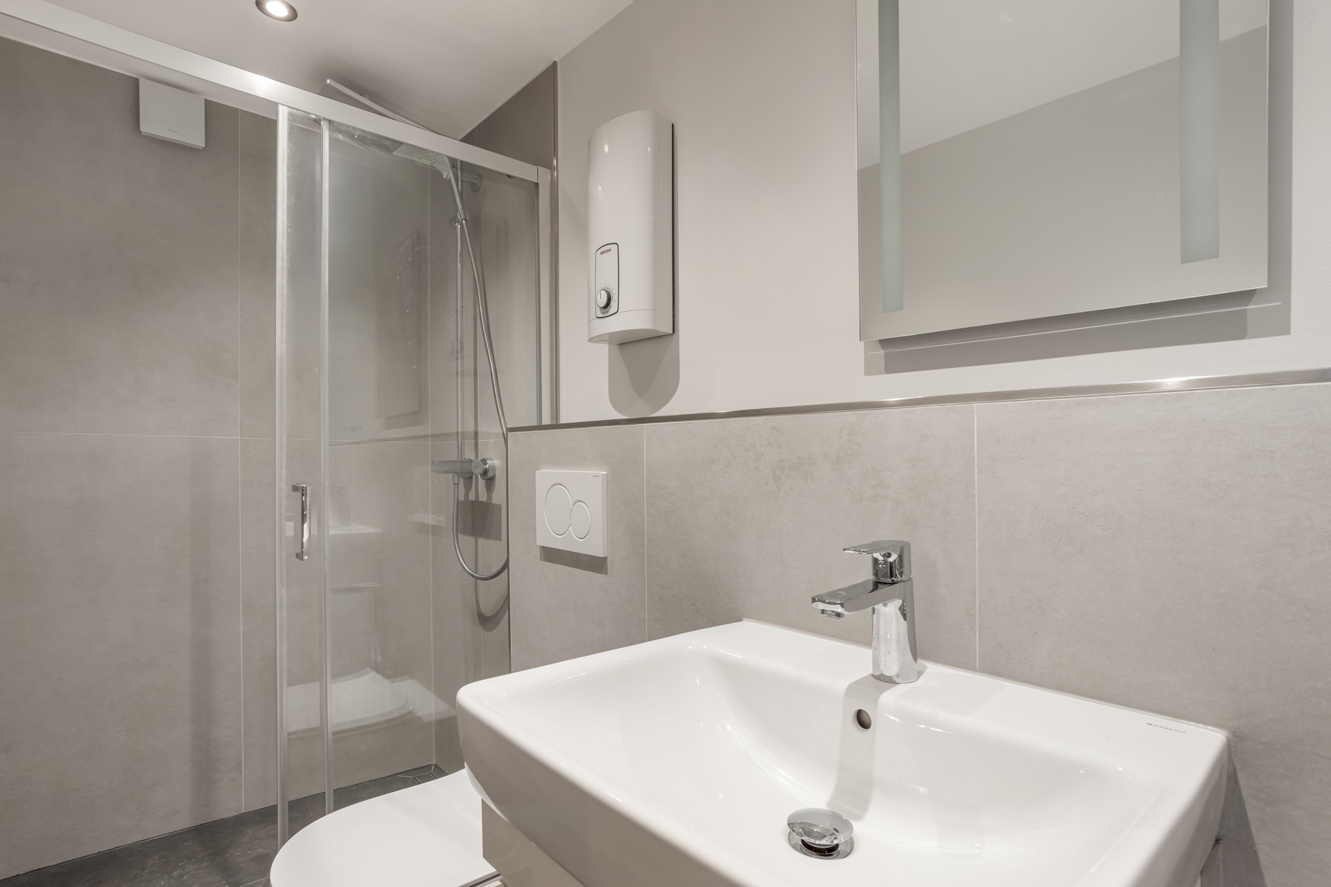 Modernes Badezimmer mit Waschbecken, Spiegel, Dusche und Toilette.