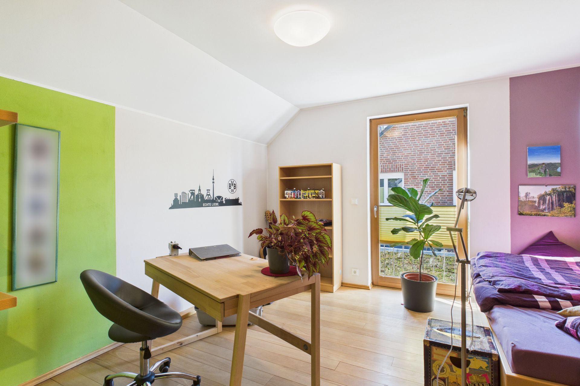 Helles Arbeitszimmer mit Schreibtisch, Stuhl, Regal, Pflanze und Einzelbett.