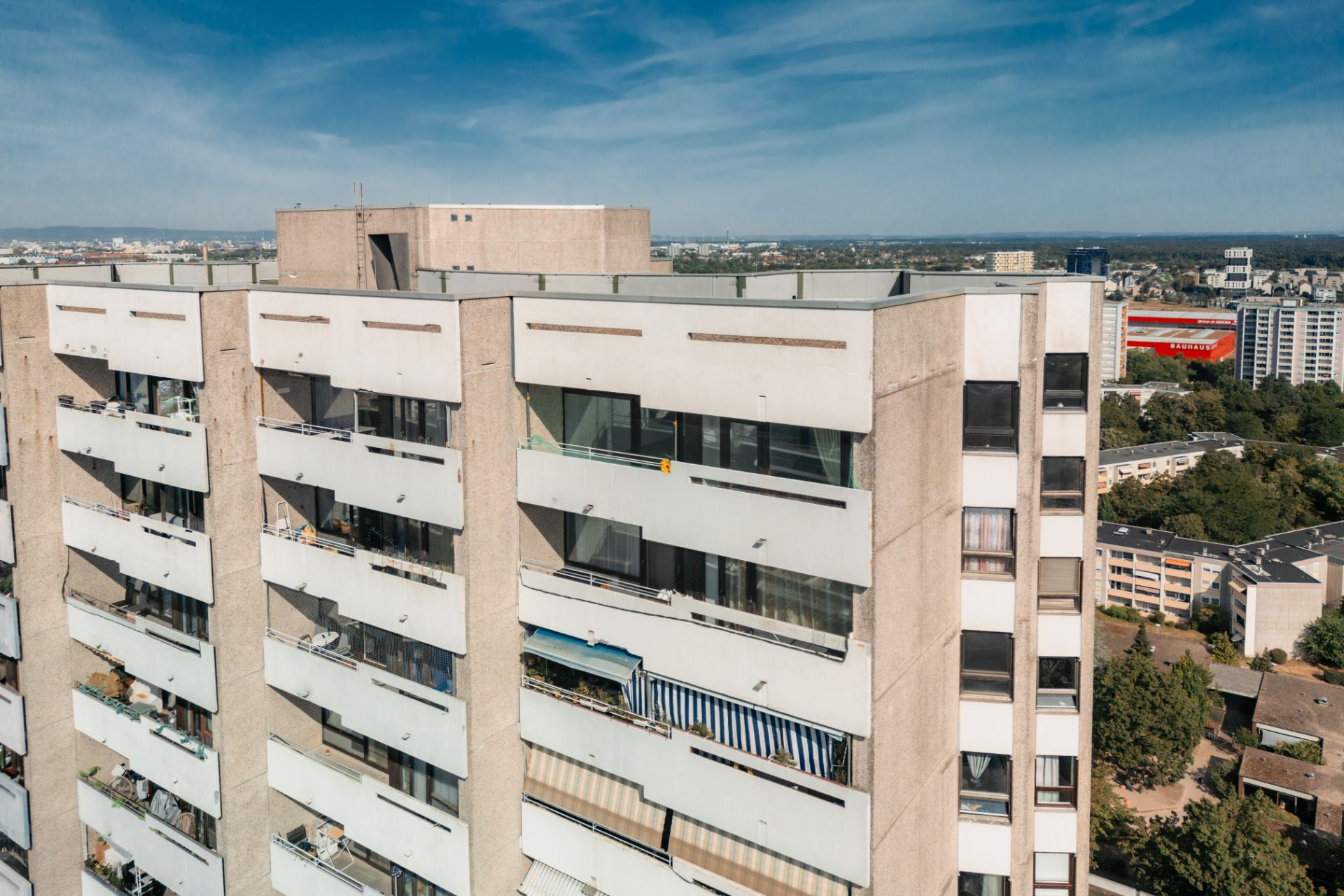 Mehrstöckiges Wohnhaus mit Balkonen und Blick auf die Stadt bei sonnigem Wetter.