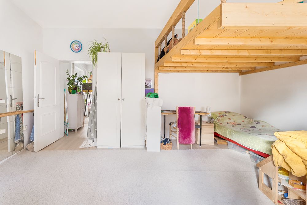 Helles Zimmer mit Hochbett, Schreibtisch, Bett, Kleiderschrank und Pflanzen.