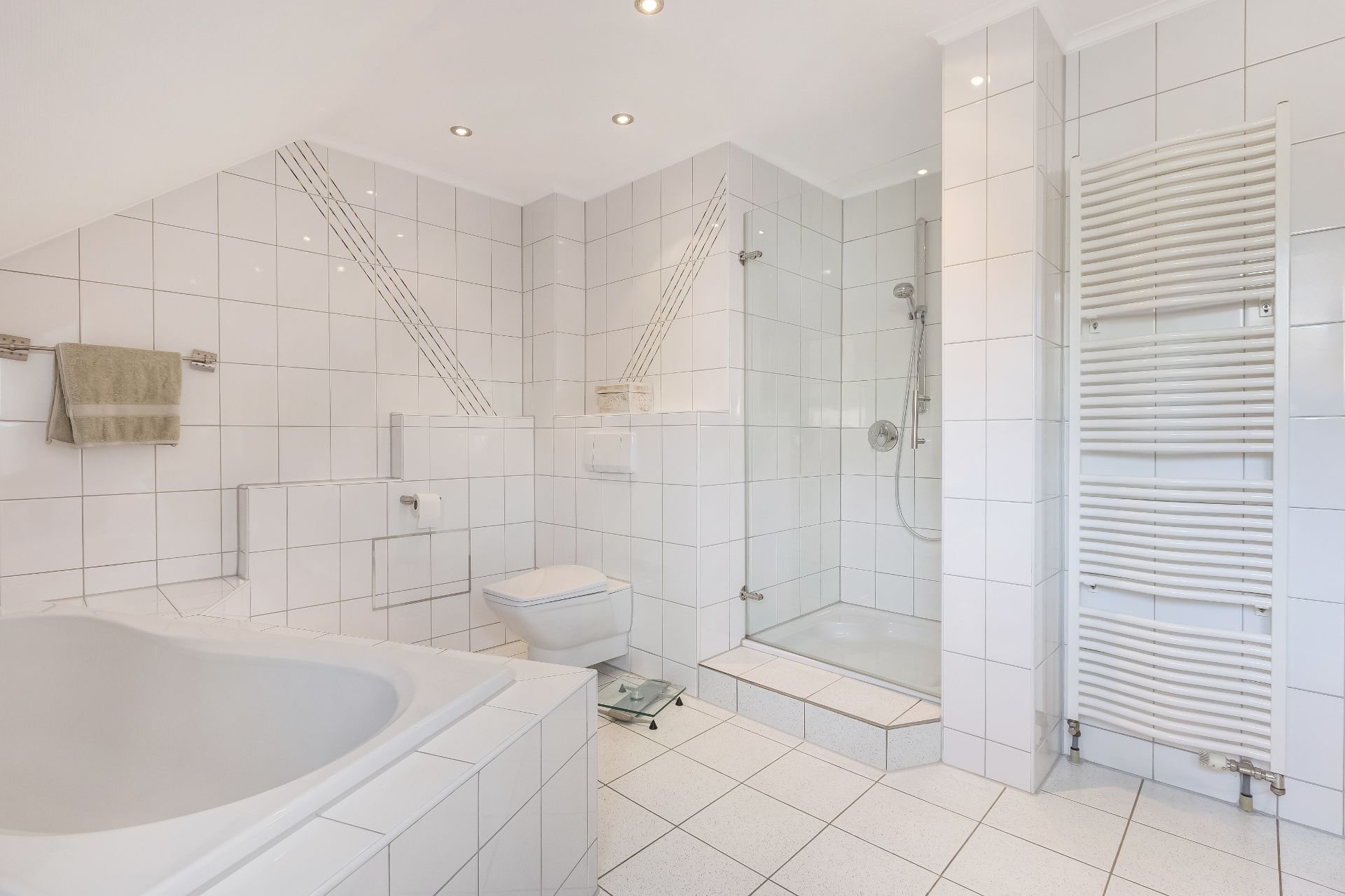 Modernes Badezimmer mit Badewanne, Dusche, WC und Handtuchheizkörper, alles in weißen Fliesen.