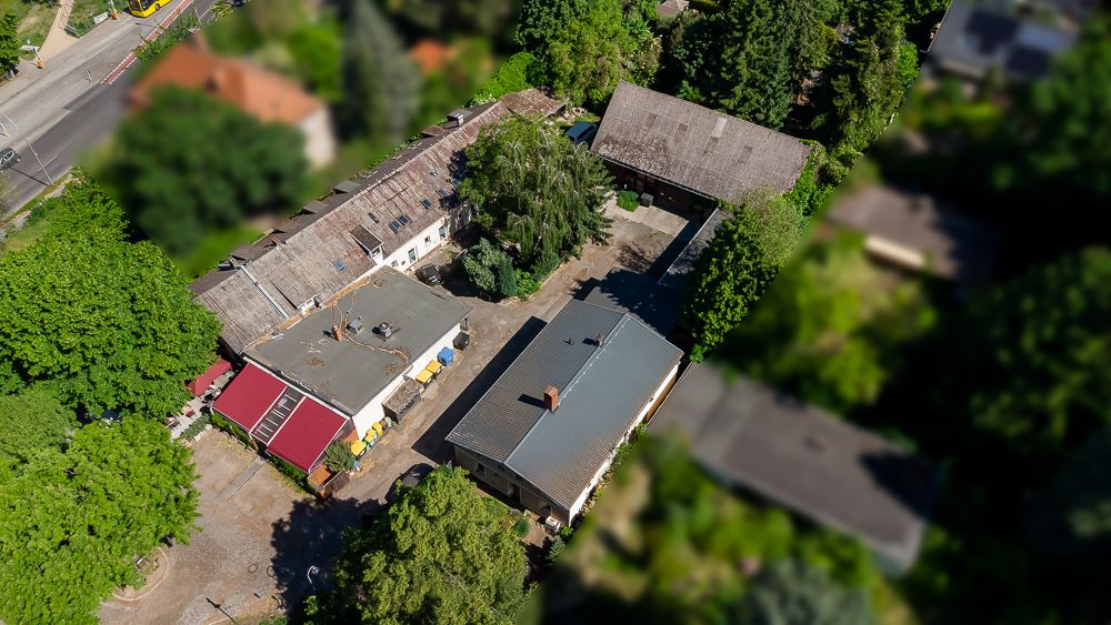 Luftaufnahme mehrerer Wohngebäude mit Innenhof und umgebenden Bäumen.