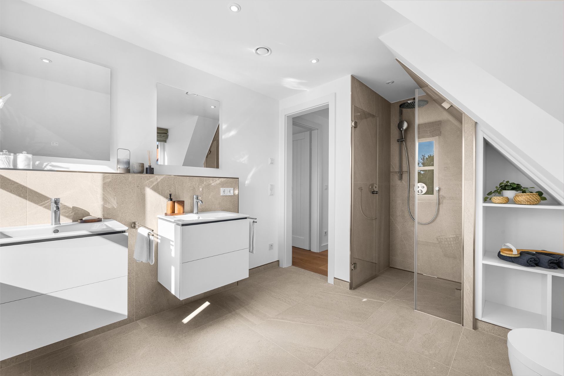 Modernes Badezimmer mit zwei Waschbecken, offener Dusche und Regalen unter einer Dachschräge.