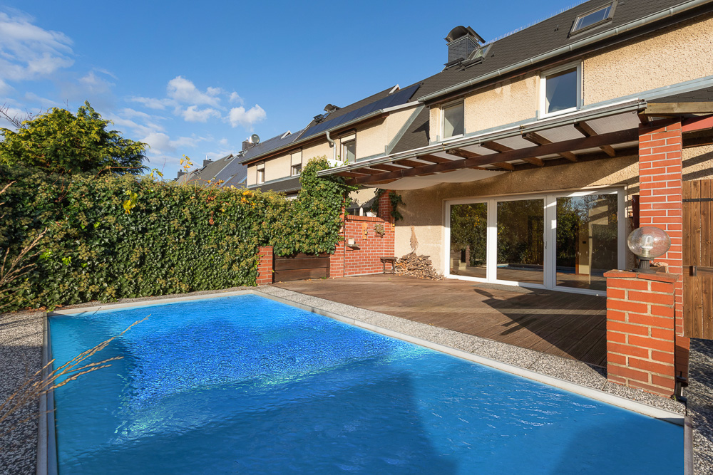 Garten mit kleinem Pool, Holzboden und überdachter Terrasse an einem Wohnhaus.