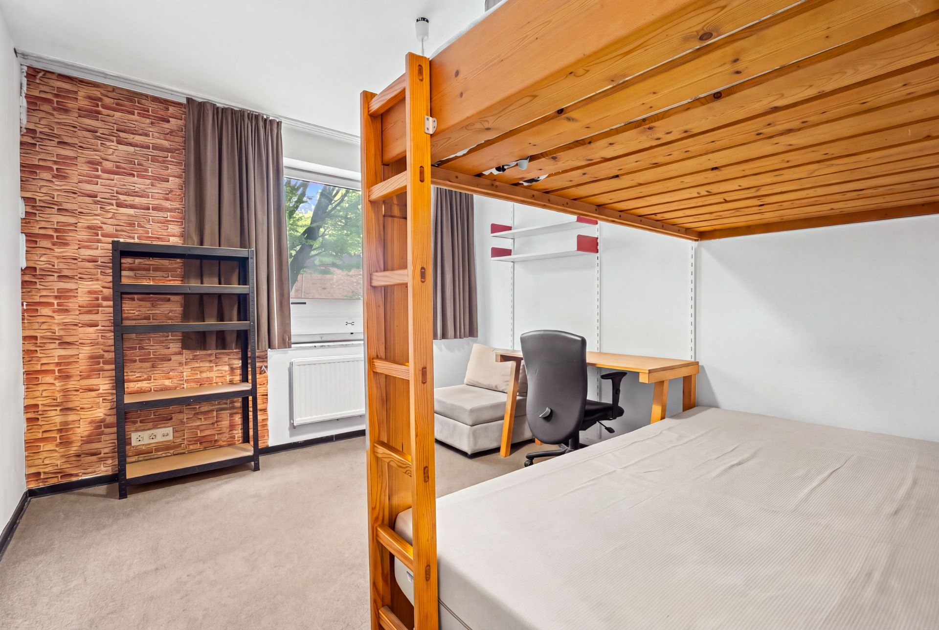 Helles Zimmer mit Hochbett, Schreibtisch, Regal, Sessel und großem Fenster mit braunen Vorhängen.