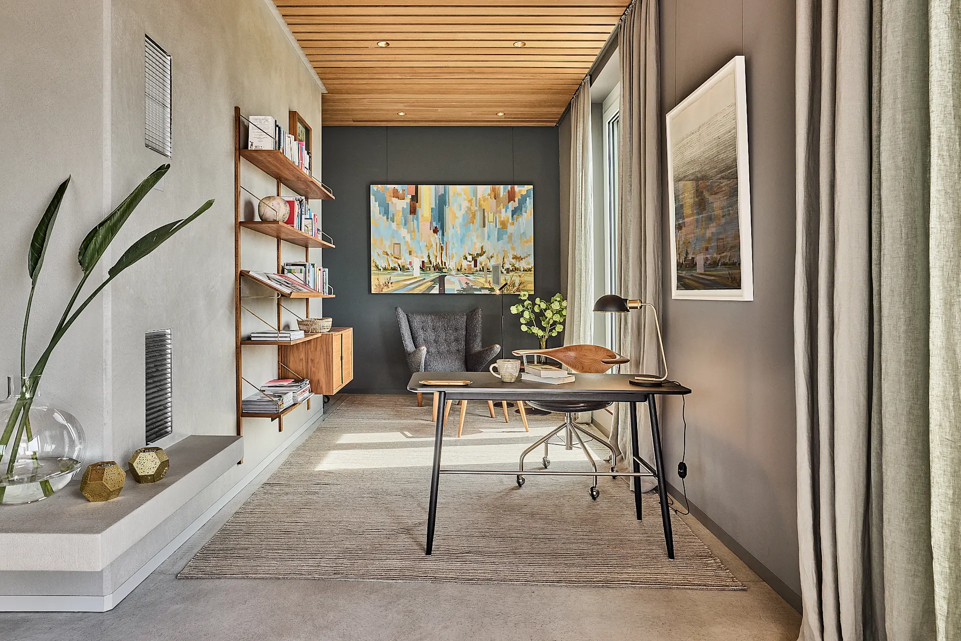 Modernes Arbeitszimmer mit Schreibtisch, Regal, Sessel und bunter Wandkunst.
