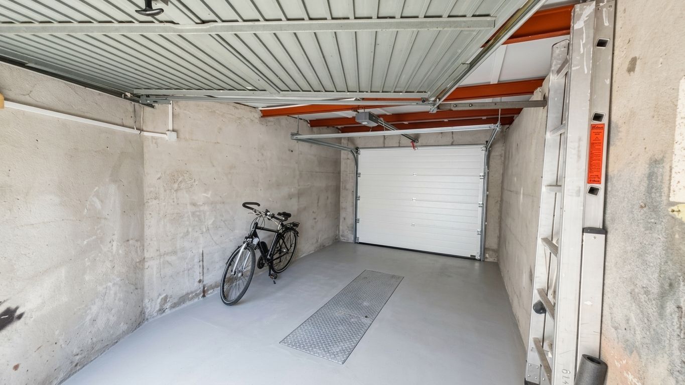 Leere Garage mit Fahrrad und Leiter an der Wand.
