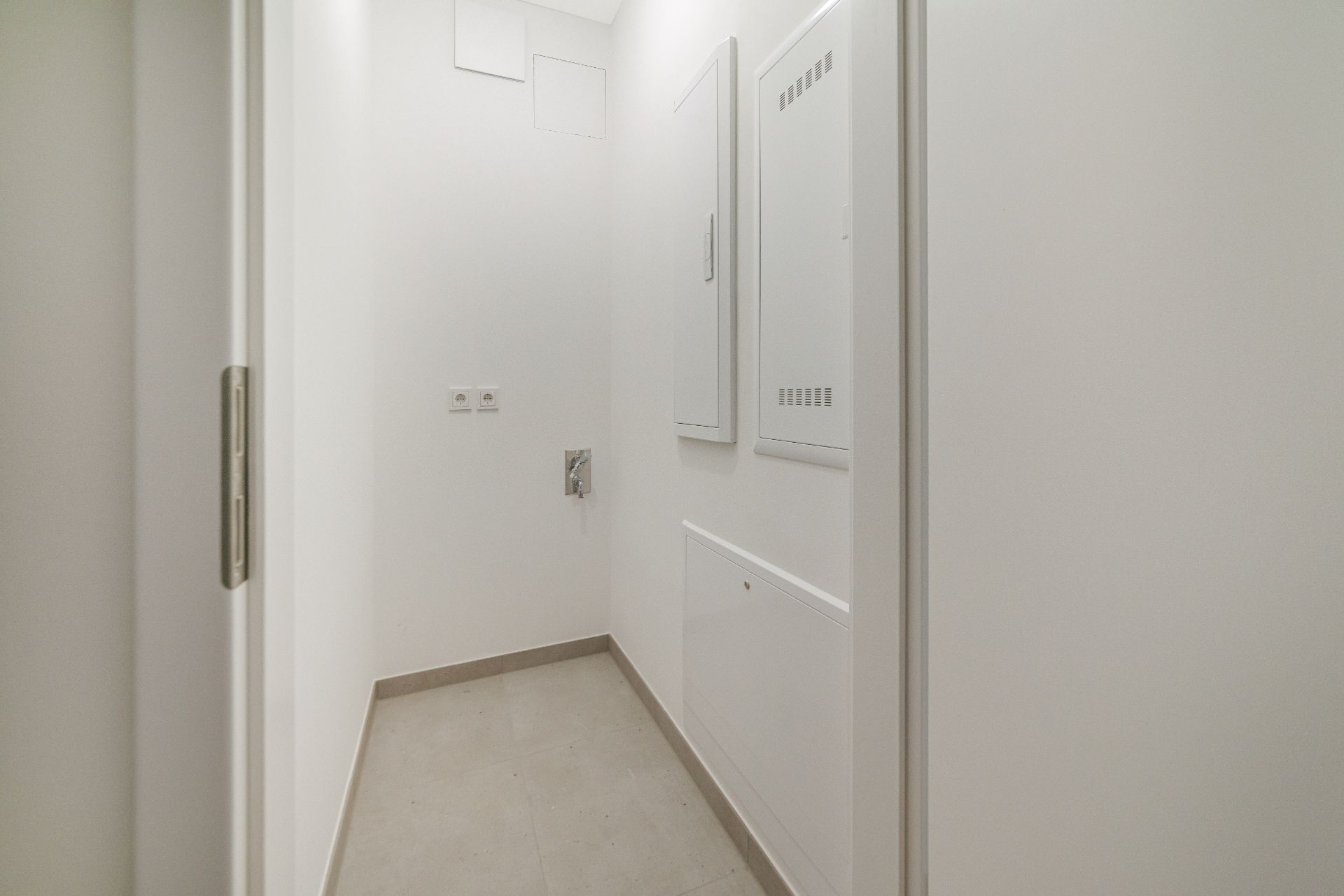 Heller, schmaler Flur mit weißen Wänden und Wandverkleidungen, Steckdosen an der Wand.
