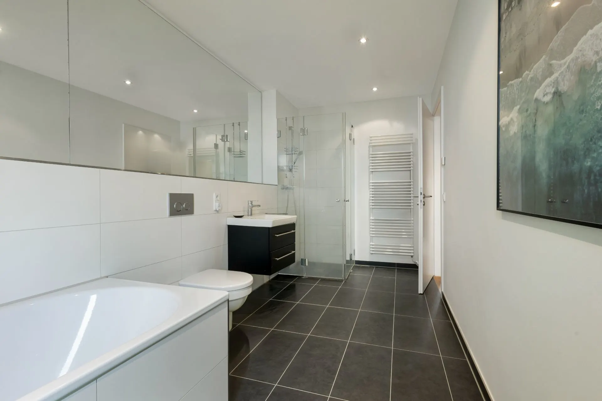 Modernes Badezimmer mit Badewanne, Dusche, WC, Waschbecken und Wandheizkörper.