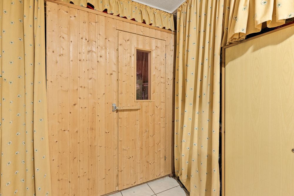 Holztür mit Fenster, umgeben von gelbem Vorhang mit Blumenmuster in einem Raum.