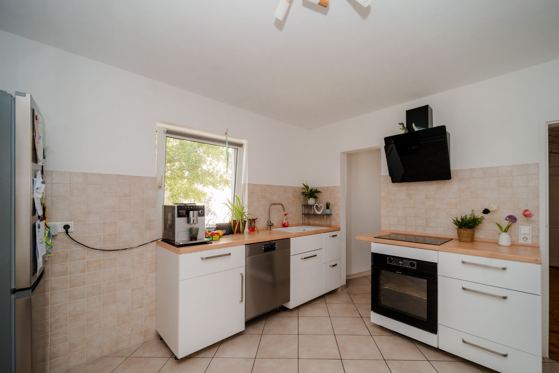 Moderne Küche mit weißen Schränken, großem Fenster, Herd und Spülmaschine.