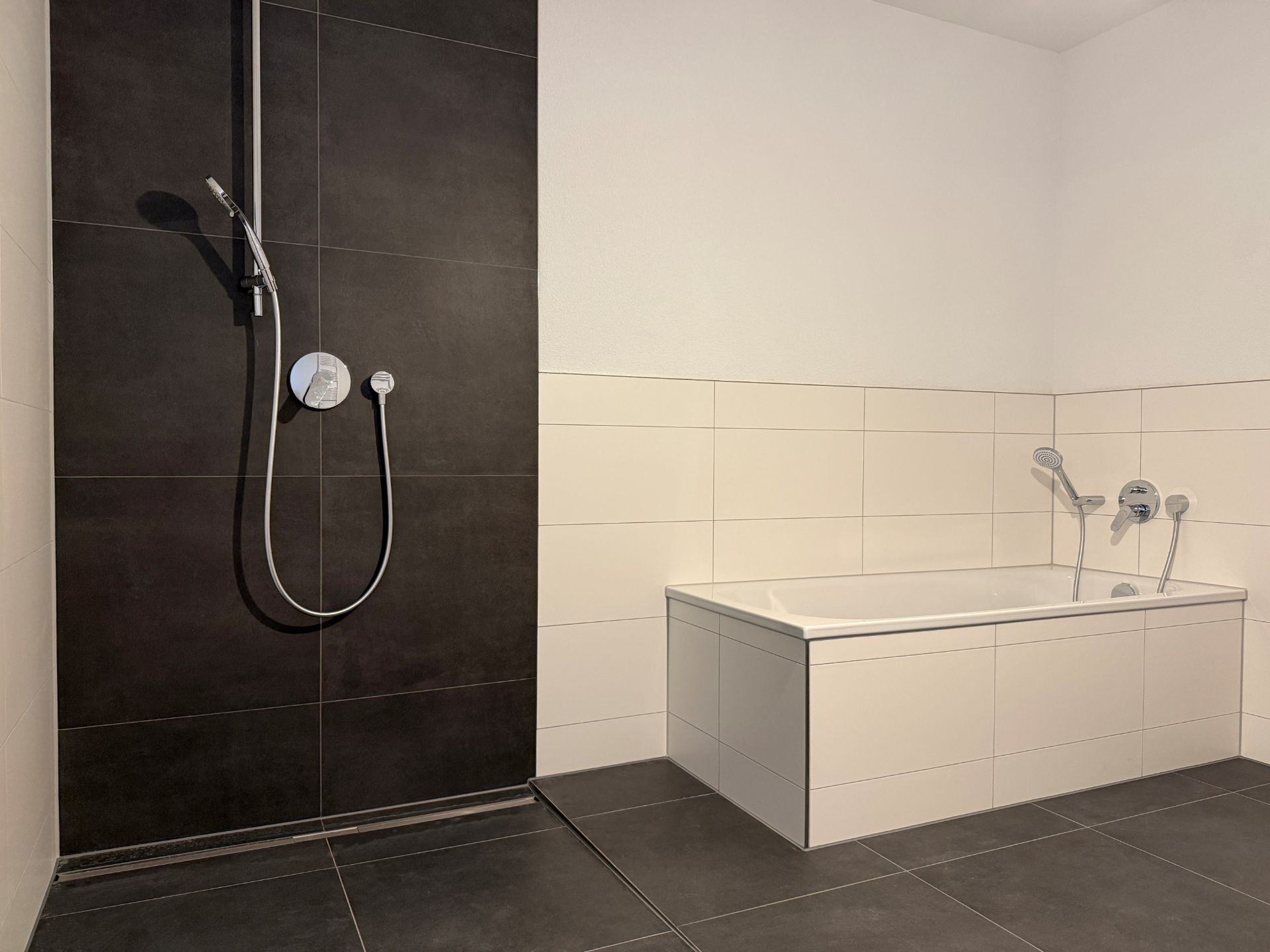 Modernes Badezimmer mit begehbarer Dusche und Badewanne, gefliest in Schwarz und Weiß.