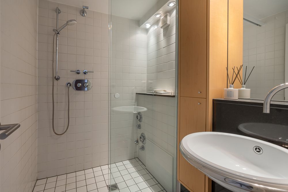 Modernes Badezimmer mit begehbarer Dusche, Waschbecken und Holzmöbeln.
