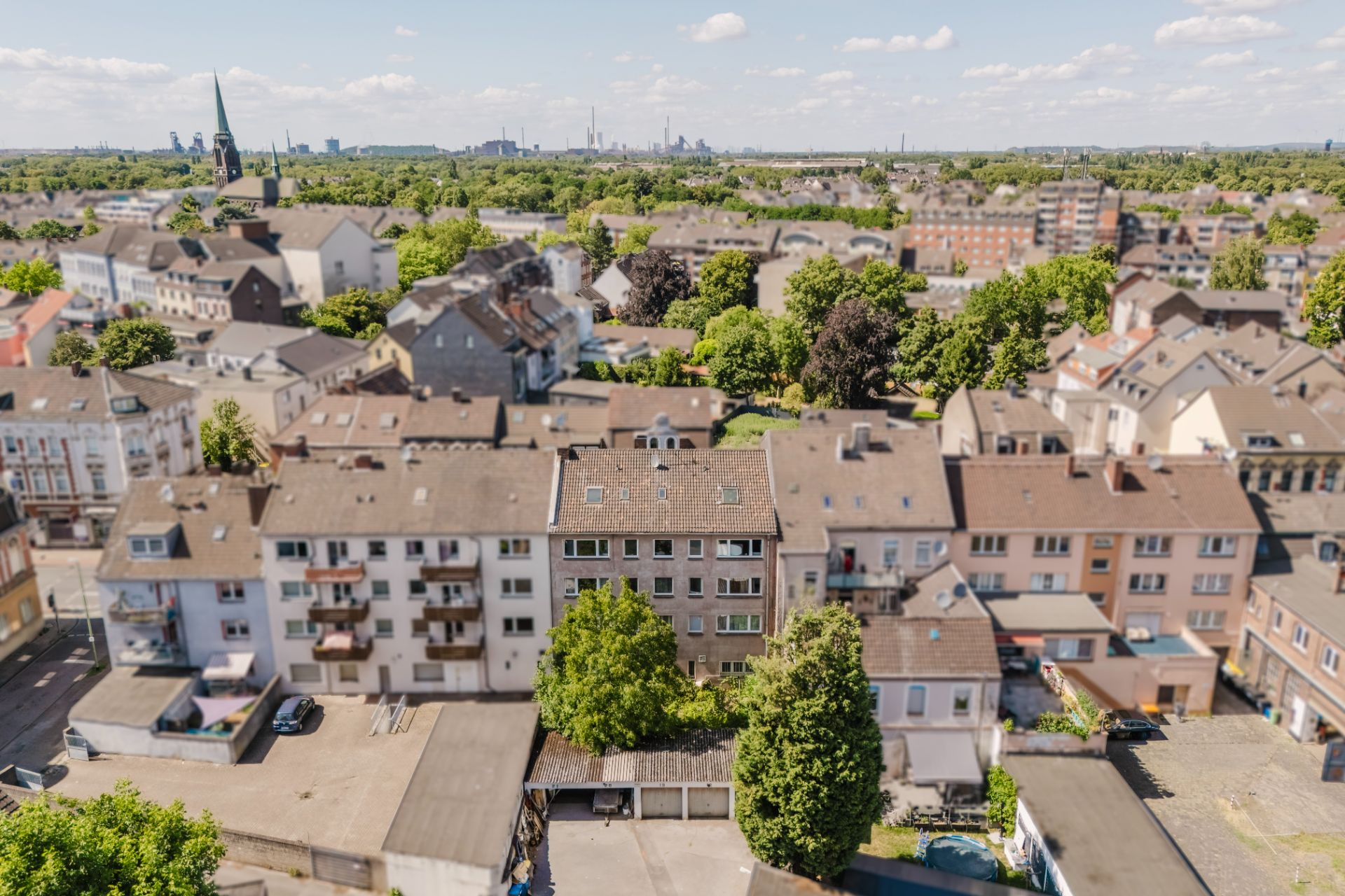 Blick auf eine Wohngegend mit mehreren mehrstöckigen Häusern und viel Grün im Hintergrund.