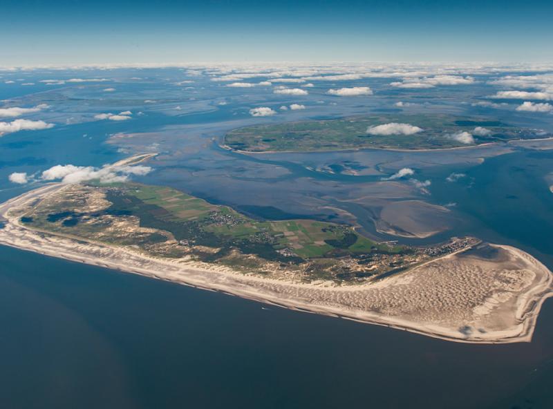 Luftaufnahme einer Insel mit Sandstränden, Feldern und kleinen Ortschaften im Meer.