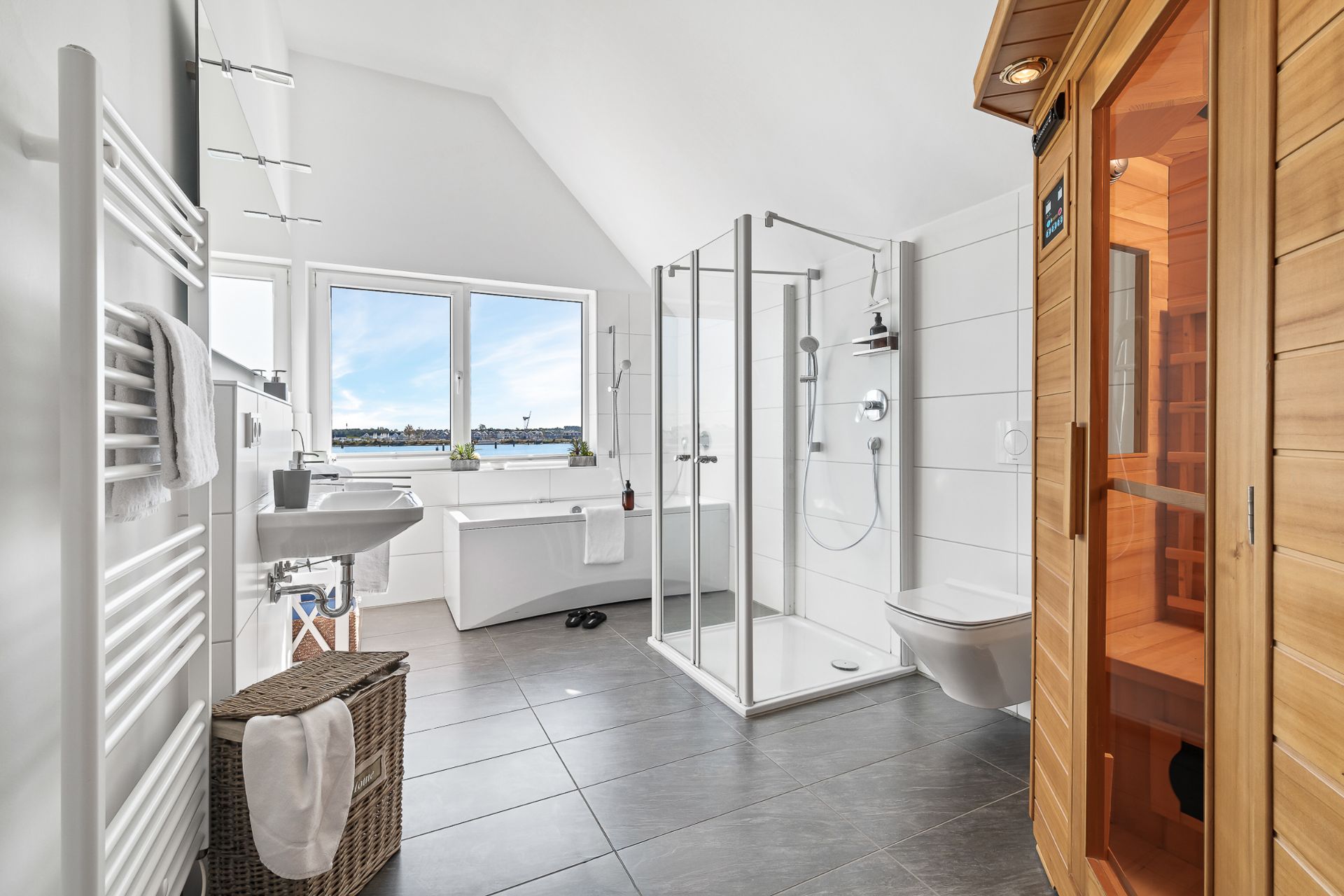 Modernes Badezimmer mit Dusche, Badewanne, Sauna und großem Fenster, weiße Fliesen und grauer Boden.
