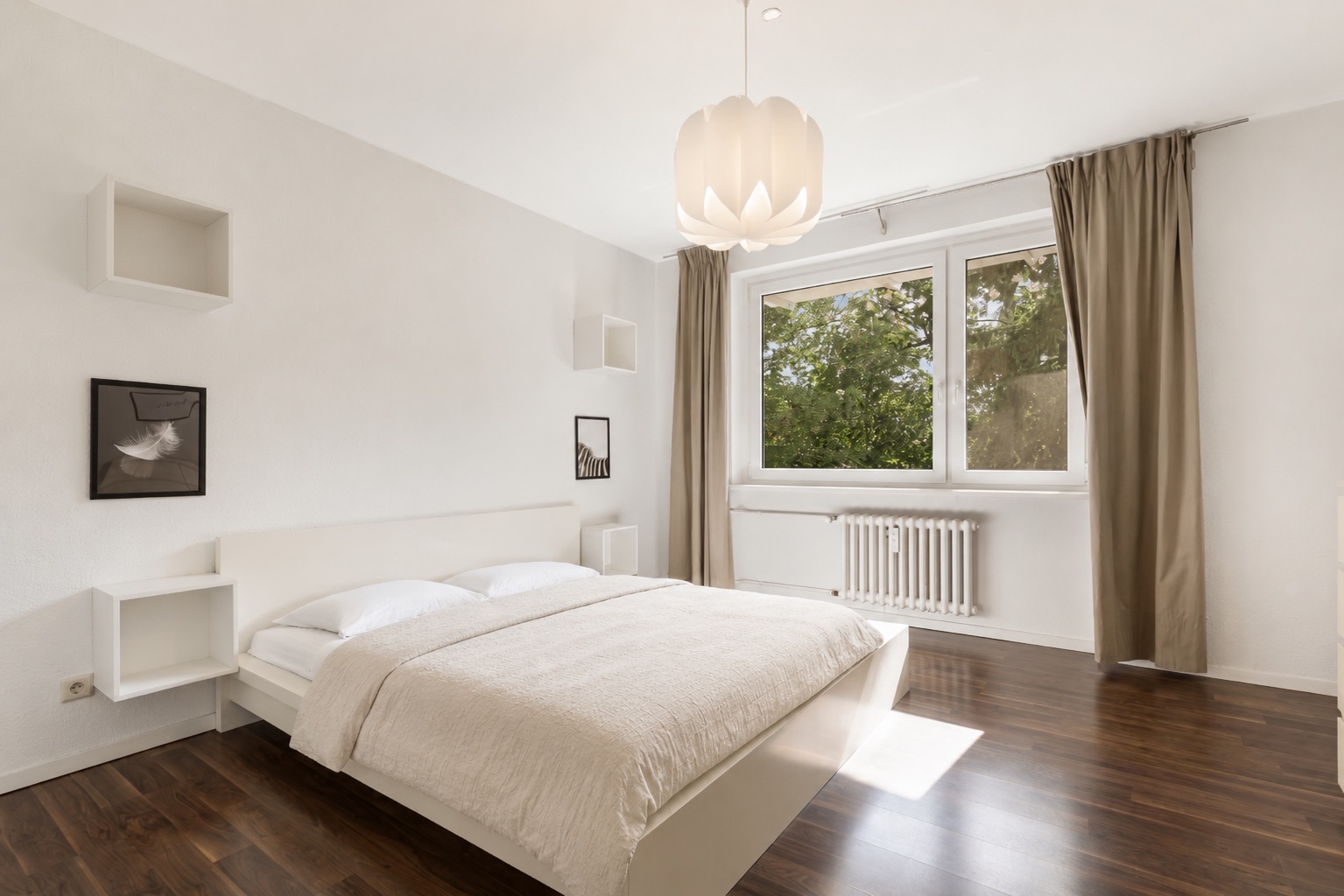 Helles Schlafzimmer mit Doppelbett, großen Fenstern, braunen Vorhängen und Holzfußboden.