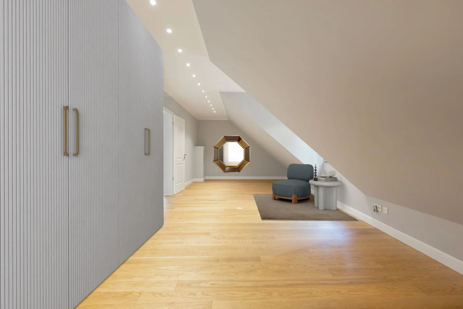 Heller Dachbodenraum mit Holzfußboden, Einbauschrank und Sessel unter einer Schräge.