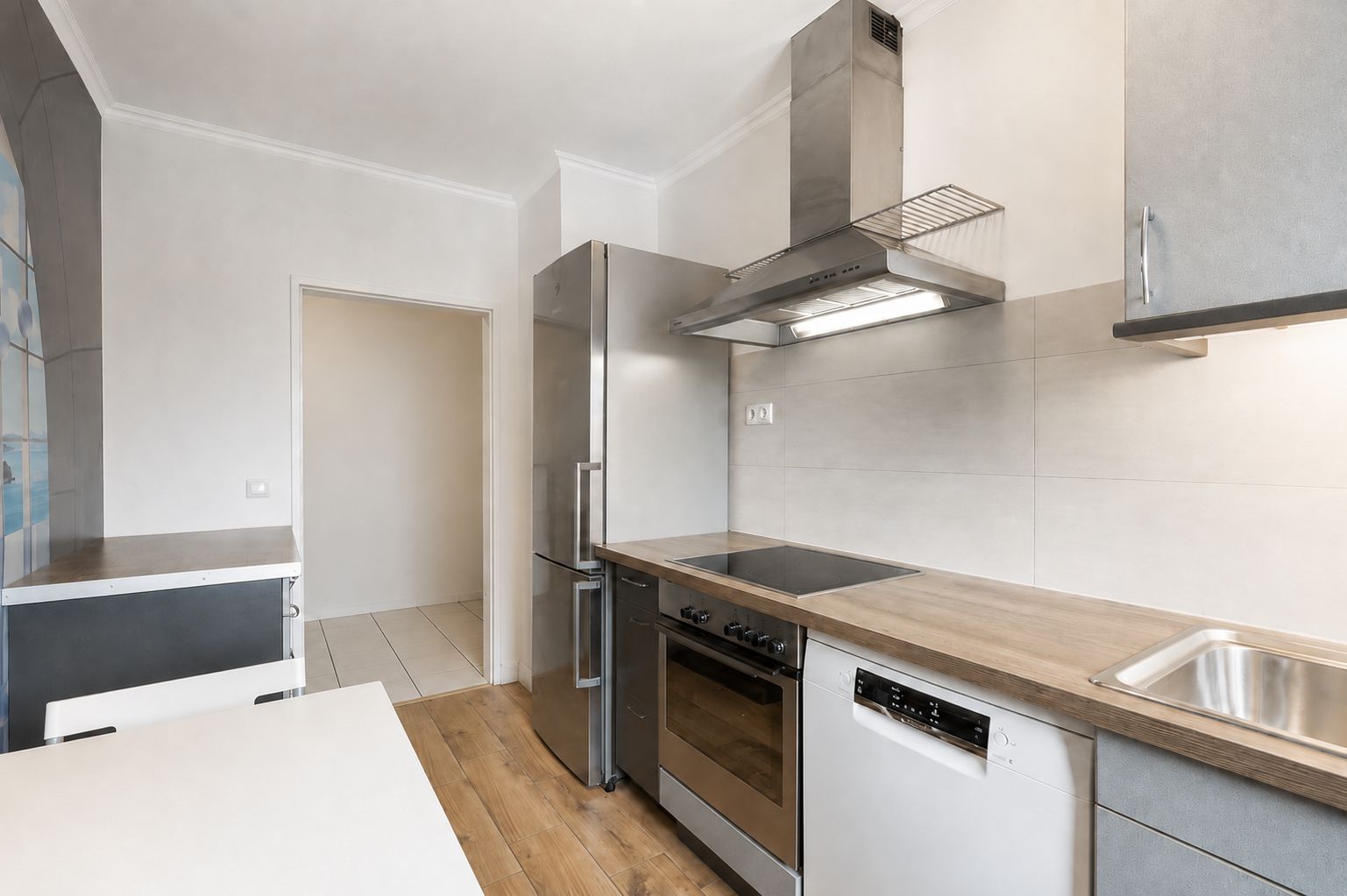 Moderne Küche mit Herd, Backofen, Edelstahlkühlschrank und Spüle, Holzboden.