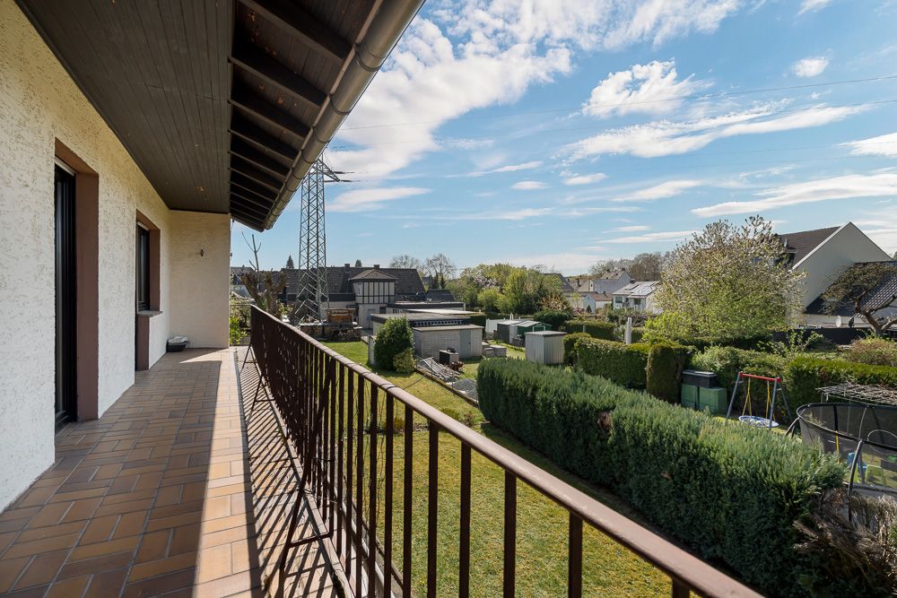 Balkon mit braunem Geländer und Blick auf Garten und Nachbarhäuser.