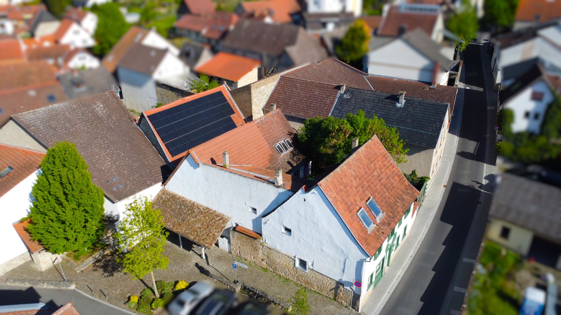Luftaufnahme mehrerer Wohnhäuser mit roten Dächern und Solarpanels in einer Wohnsiedlung.