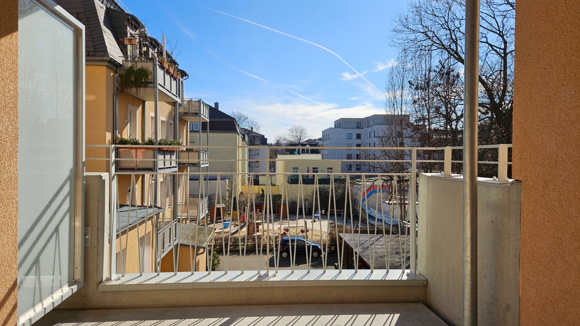 Blick von einem Balkon auf einen Innenhof mit Spielplatz und Wohngebäuden.