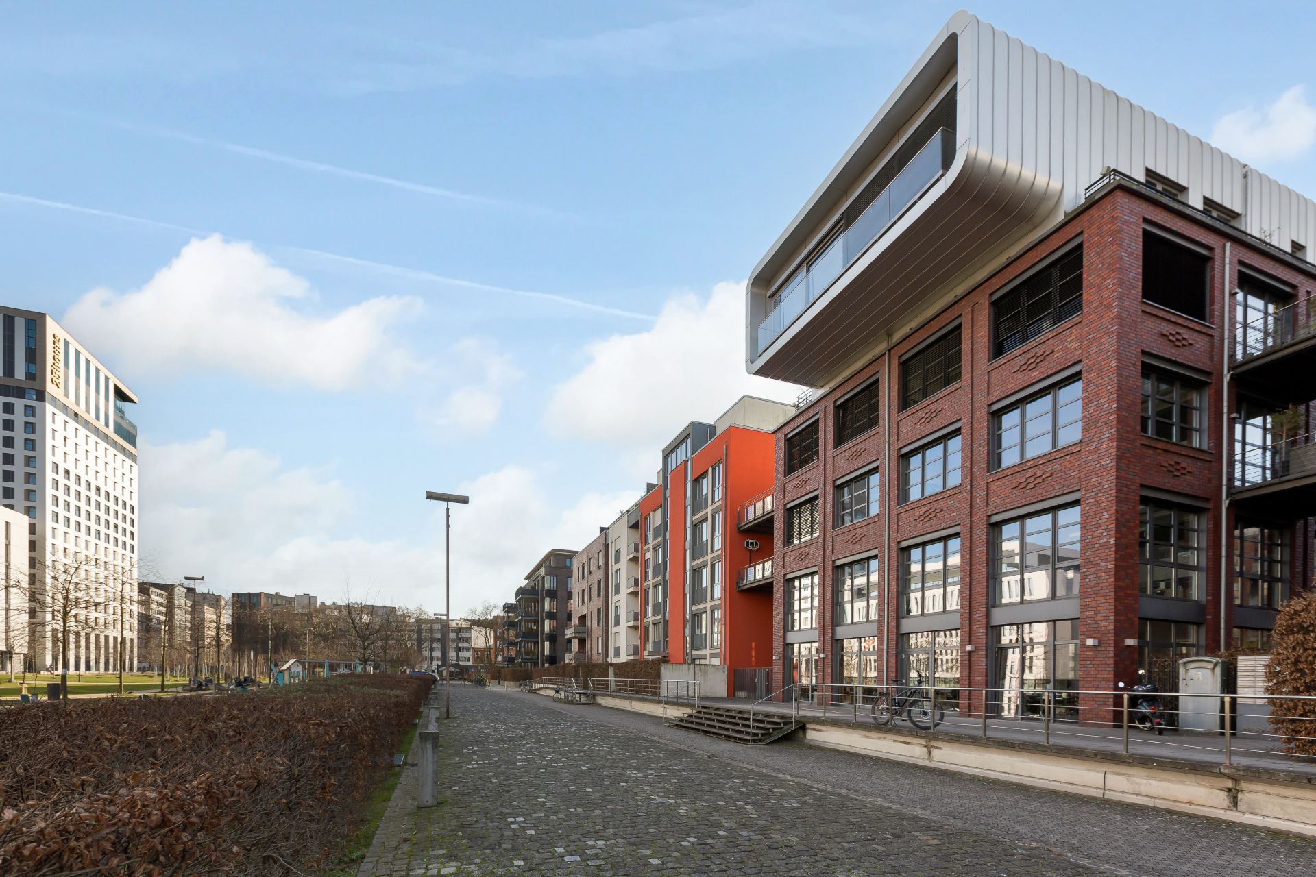 Moderne mehrstöckige Wohngebäude mit großen Fenstern an einer gepflasterten Straße.