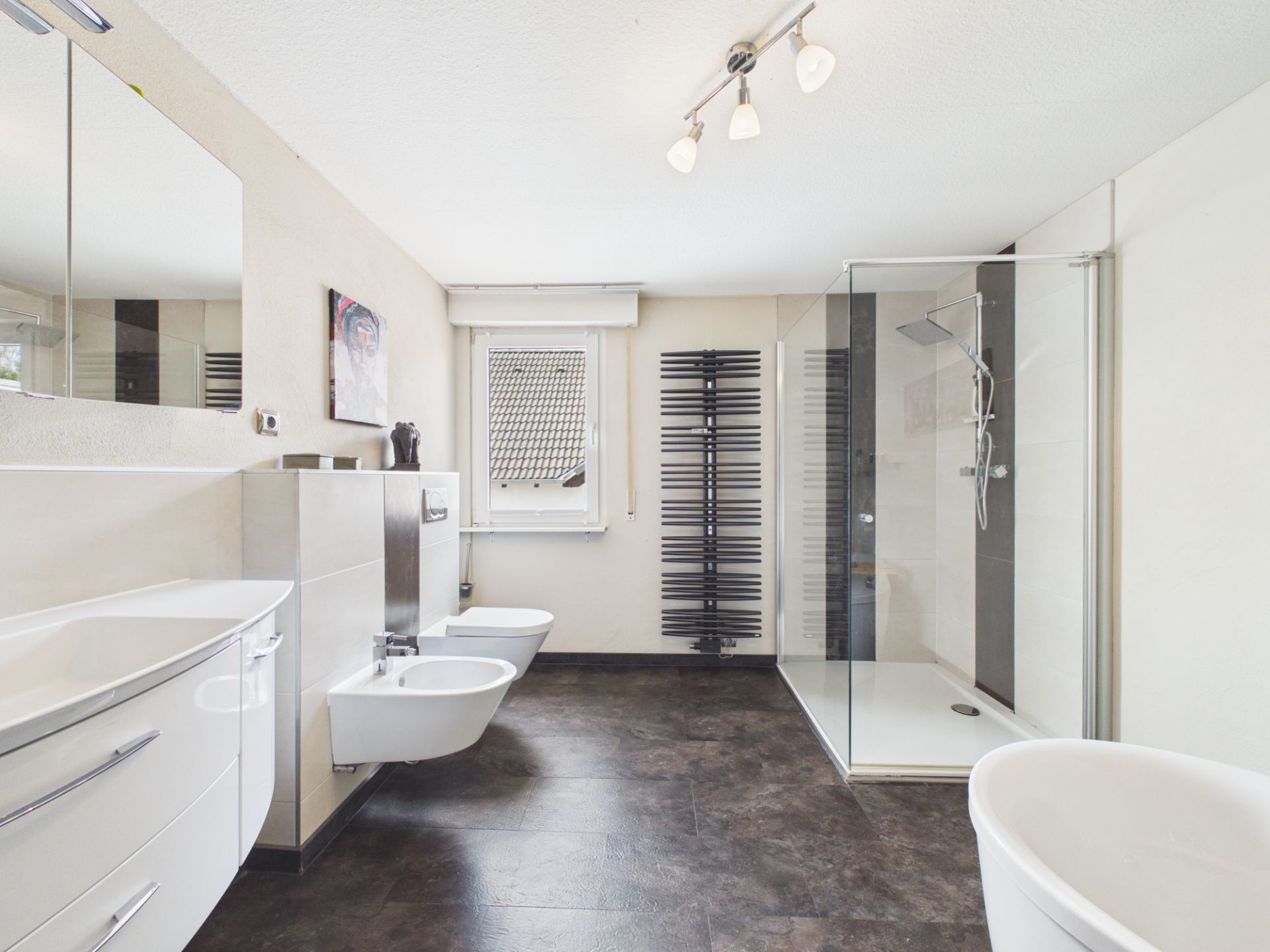 Modernes Badezimmer mit Dusche, Badewanne, WC, Bidet, Waschbecken und Fenster.