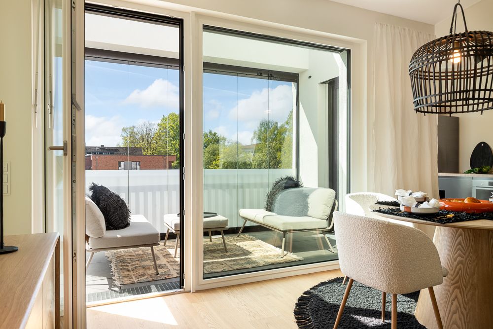 Helles Wohnzimmer mit Essbereich, Glastür zu möblierter Loggia und Blick ins Grüne.