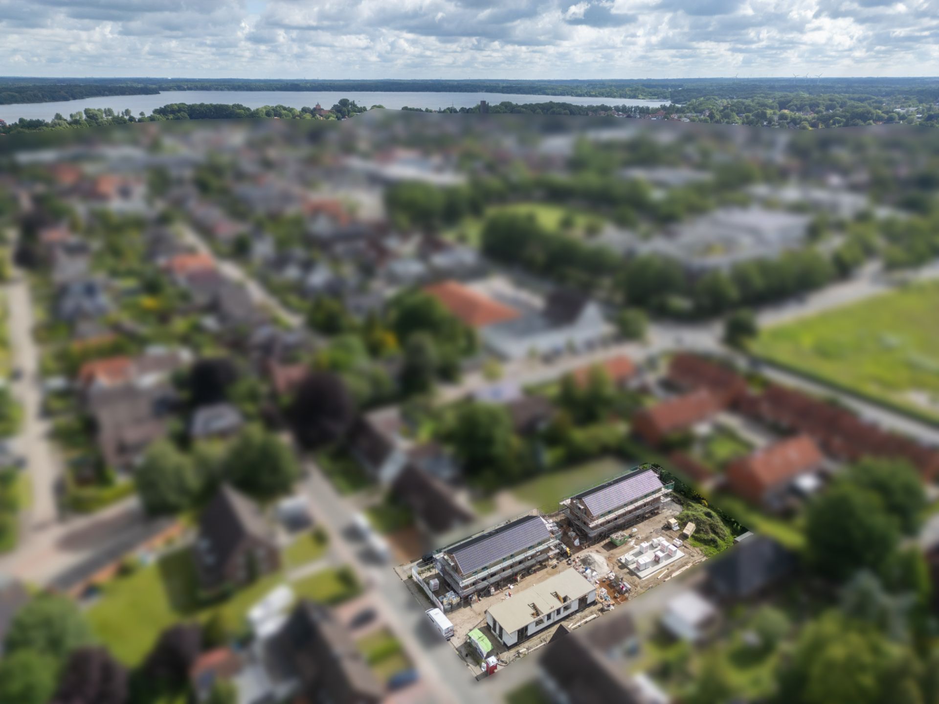 Luftaufnahme einer Wohngegend mit mehreren Häusern und einer Baustelle im Vordergrund.