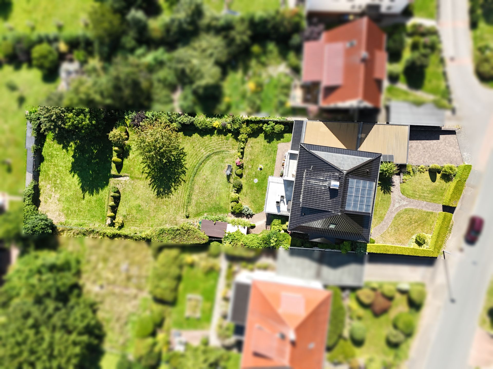 Luftbild eines Wohnhauses mit großem Garten und einer Solaranlage auf dem Dach.