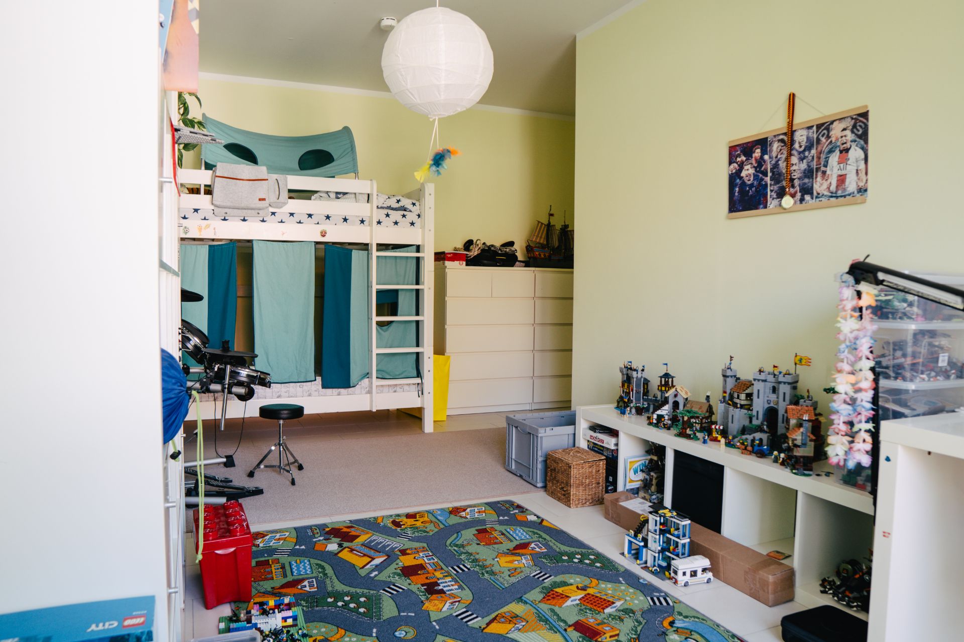 Kinderzimmer mit Hochbett, Teppich mit Straßenmotiv und Spielzeugregalen.