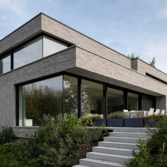 Modernes zweistöckiges Wohnhaus mit großen Fenstern und Garten, außen Treppe zum Eingang.