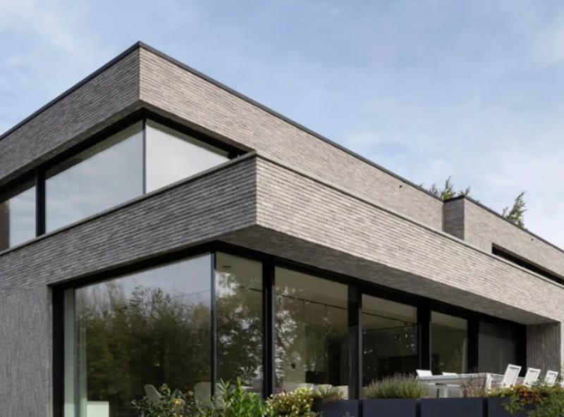 Modernes zweistöckiges Wohnhaus mit großen Fenstern und Garten, außen Treppe zum Eingang.