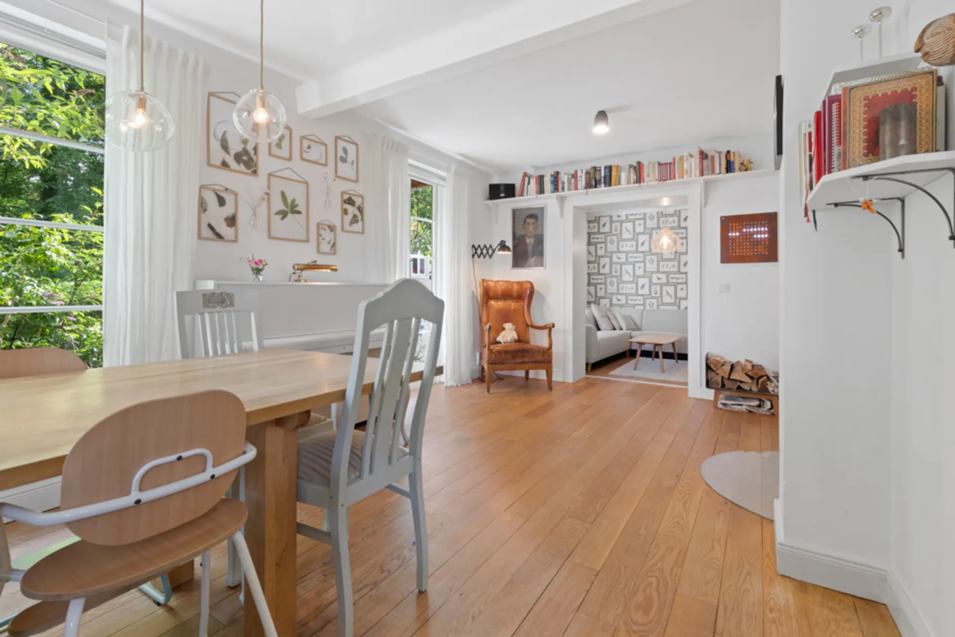 Helles Esszimmer mit Holzboden, großem Tisch, Stühlen und Blick ins Wohnzimmer.
