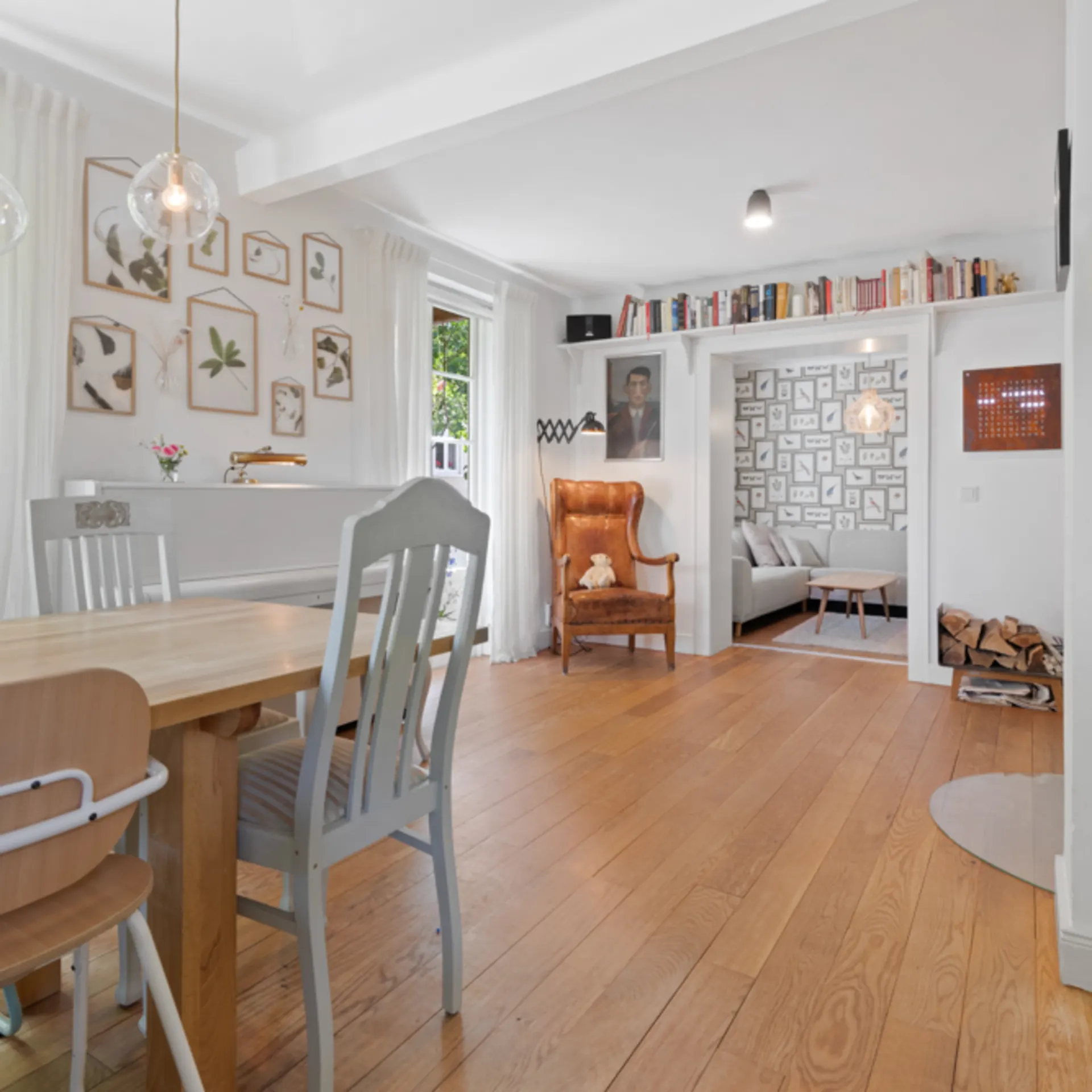 Helles Esszimmer mit Holzboden, großem Tisch, Stühlen und Blick ins Wohnzimmer.