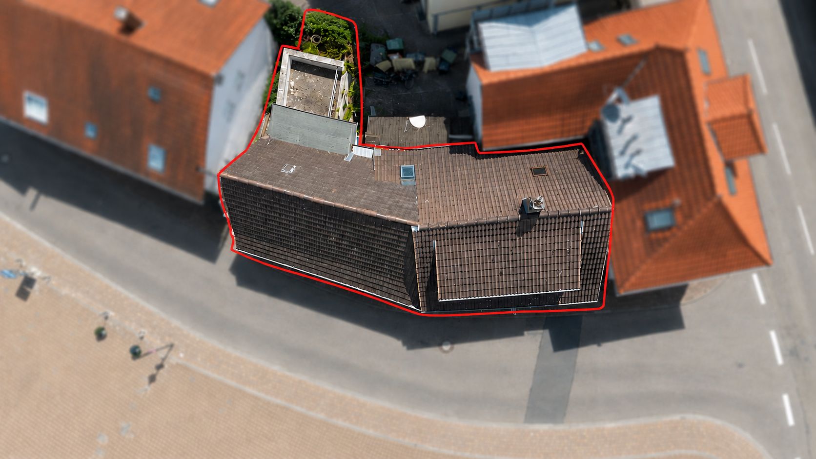Luftaufnahme eines Wohnhauses mit rot markierter Grundstücksgrenze an einer Straße.
