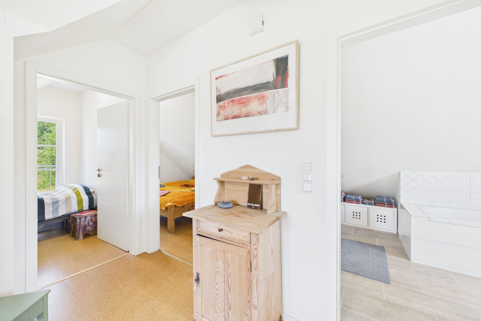 Heller Flur mit Holzmöbel, Türen führen zu Schlafzimmer, Kinderzimmer und Bad.