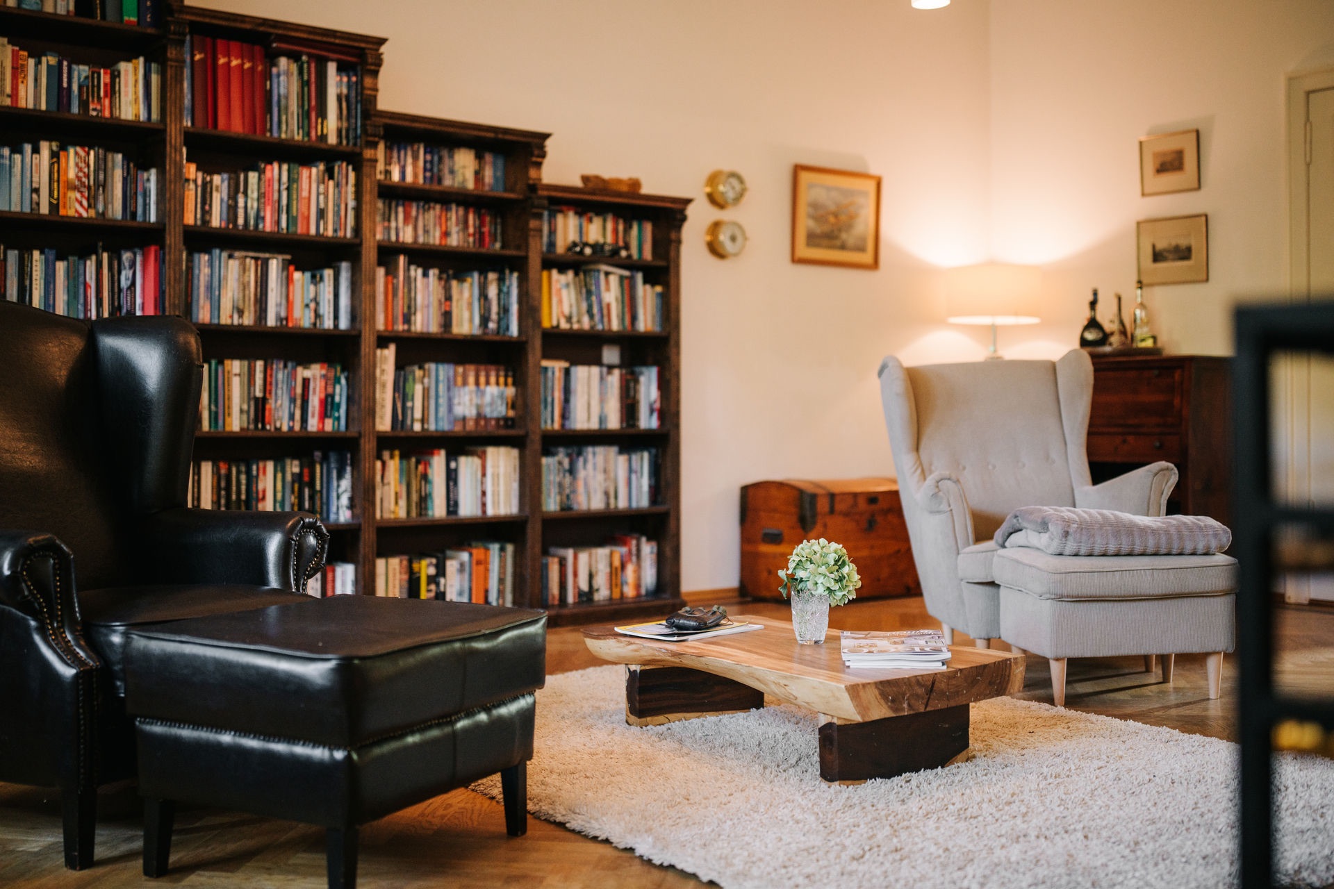 Wohnzimmer mit Bücherregalen, Sesseln, Couchtisch, Teppich und Dekoration.